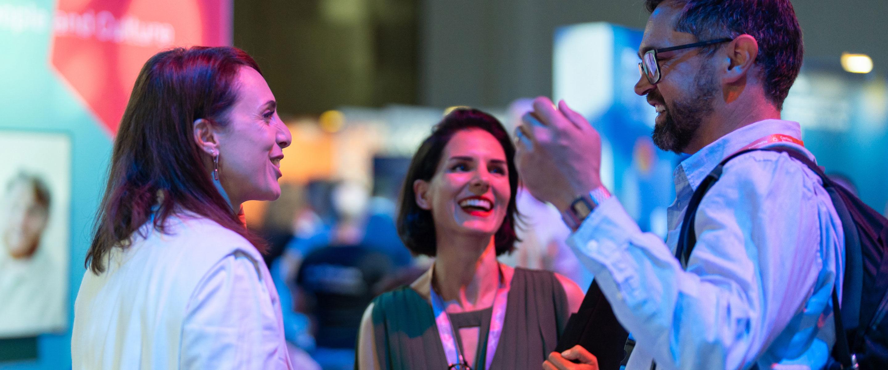 A photograph of three people engaged in conversation and laughing.